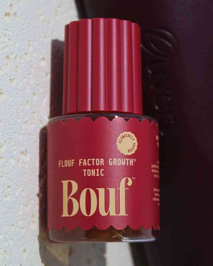 Vegan skincare serum in a pink bottle with botanical branding and clinical testing badge.