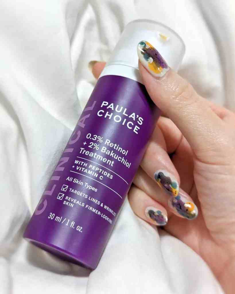 Close-up of Paula's Choice retinol serum bottle with vibrant violet label in hand.