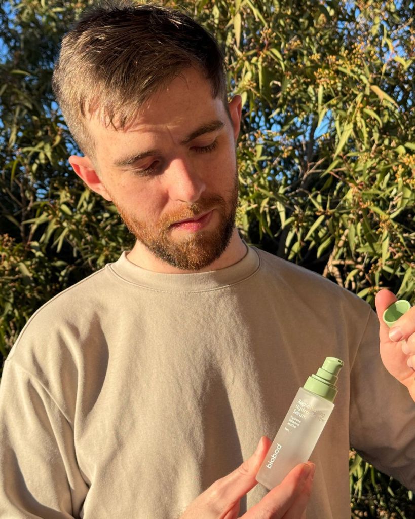 Reviewer holding the biobod Replenishing Hydra-Soothe Serum outdoors during his biobod review