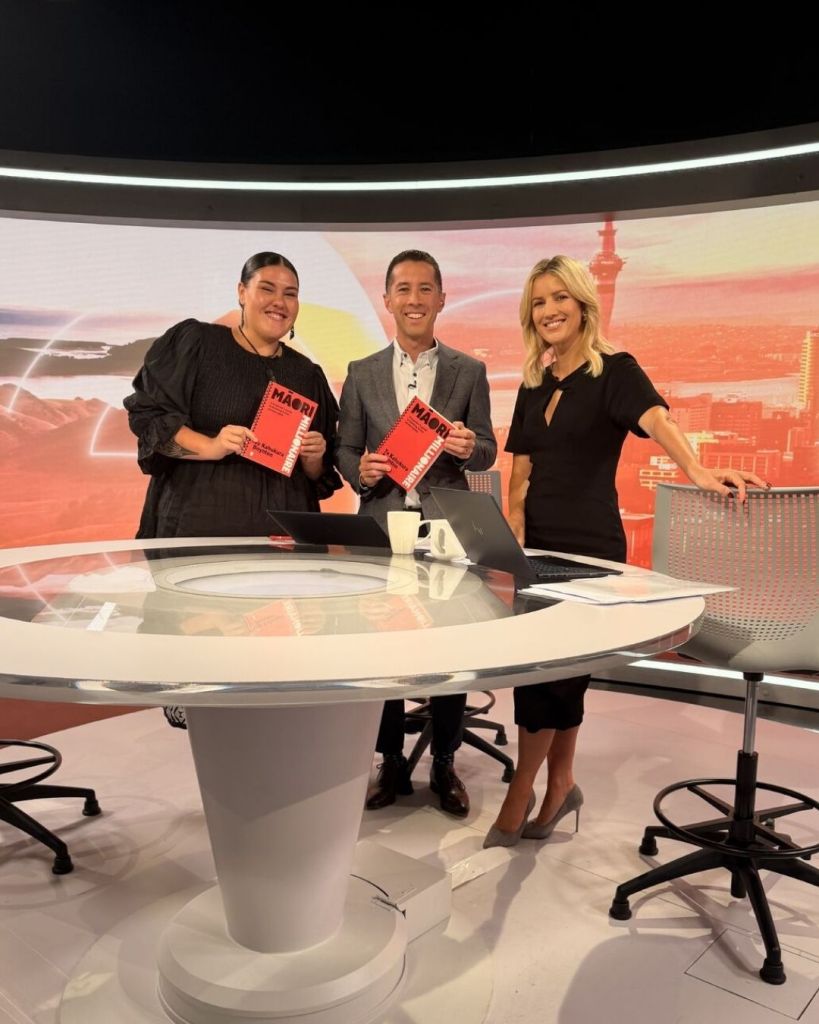 Te Kahukura Boynton holding her book Māori Millionaire during a television interview